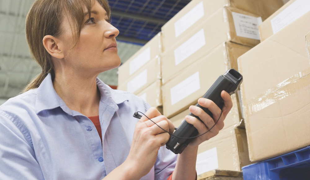 Worker using bar code reader in warehouse